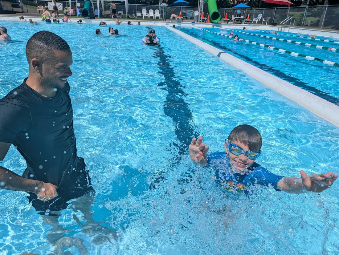 Coach Alexander cheering on a young swimmer in an outdoor pool
