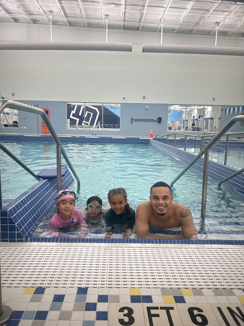 Coach Alexander with four students in the shallow end of the pool