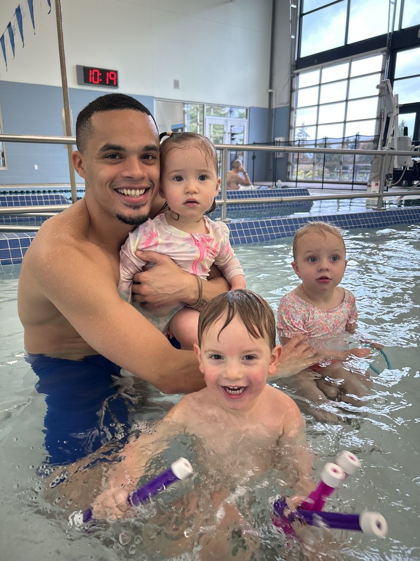 Coach Alexander with three toddlers during a group lesson